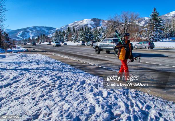 Male skier with helmet and skis is walking next to the road in the Rocky Mountains on March 02, 2015 in Park City, Utah, United States.