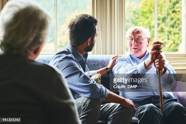 doctor comforting senior patient at home - doctor visit stock pictures, royalty-free photos & images