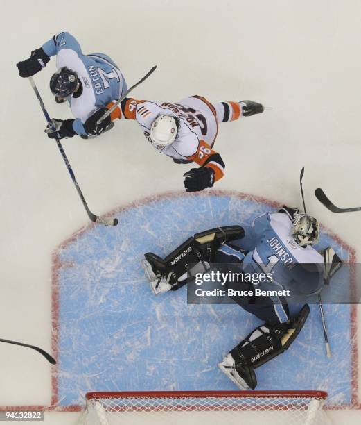 Brent Johnson of the Pittsburgh Penguins tends net against Matt Moulson and John Tavares of the New York Islanders at the Nassau Coliseum on November...