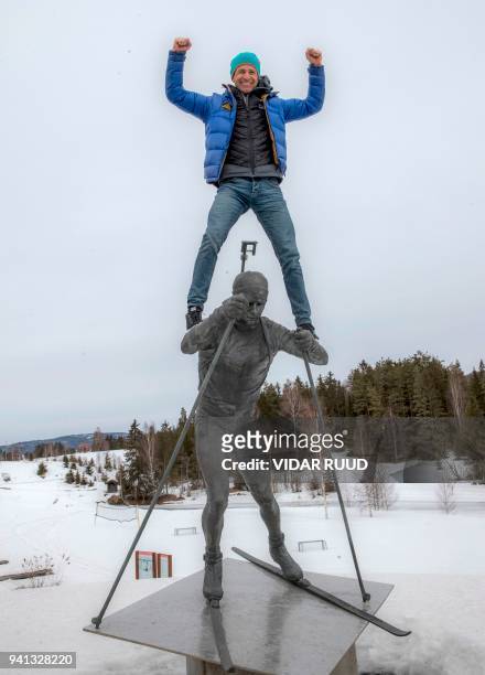 Norway's biathlon superstar Ole Einar Bjoerndalen climbs on the top of the statue of himself, after a press conference where he announced his...