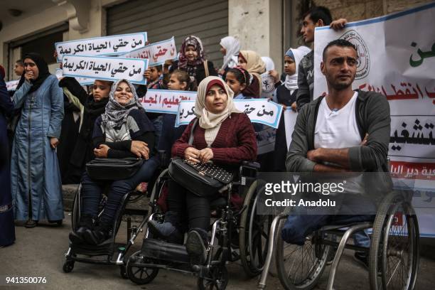 Palestinian disabled demonstrators hold placards during a protest against cutting the support services to centers for the handicapped people, by the...