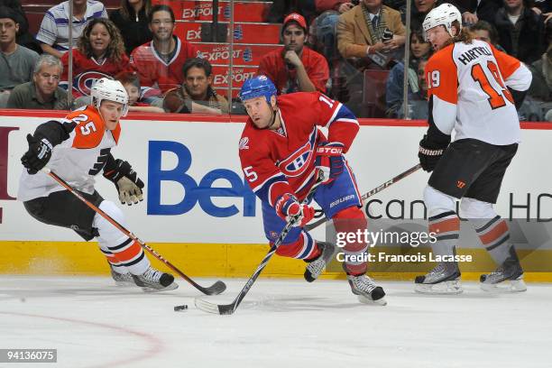 Glen Metropolit of Montreal Canadiens takes a shot in front of Matt Carle and Scott Hartnell of Philadelphia Flyers during the NHL game against the...