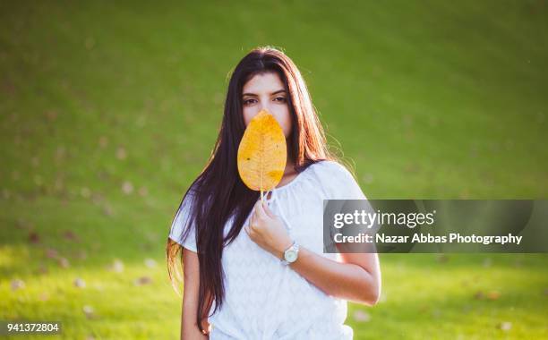 girl holding leaf and covering part of her face with it. - nazar abbas foto e immagini stock