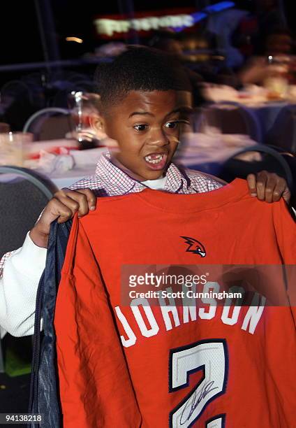 Youth in attendance shows off his autographed shirt given away at Joe Johnson's annual Santa-Lanta Holiday Event at Andretti Karting & Games Center...