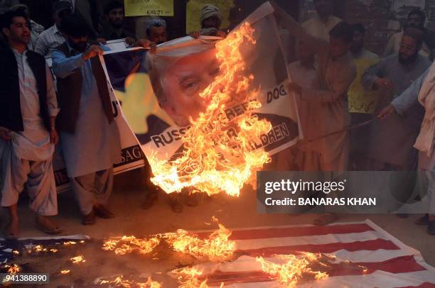 Pakistani protesters burn a US flag and a banner bearing an image of the US President Donald Trump during a demonstration against a US airstrike in...