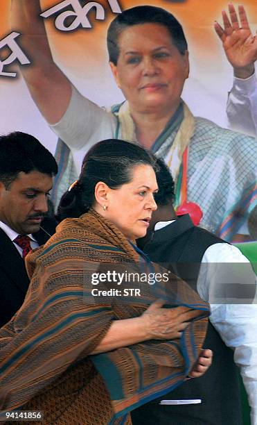 Chairperson Sonia Gandhi walks past a Congress Party poster of herself during an election rally in Ghatshila in the East Singhbhum district of...