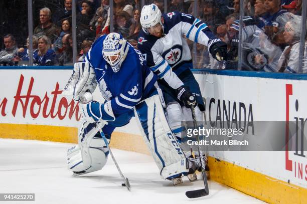 Curtis McElhinney of the Toronto Maple Leafs battles with Adam Lowry of the Winnipeg Jets during the second period at the Air Canada Centre on March...