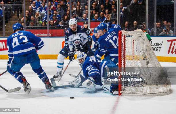 Curtis McElhinney of the Toronto Maple Leafs protects the net with Patrick Marleau, Morgan Rielly, and Nazem Kadri against Blake Wheeler of the...