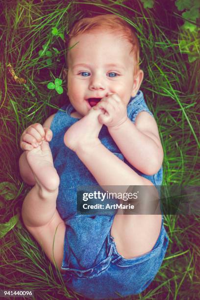 cute baby playing with his legs on the grass, from above - feet sucking stock pictures, royalty-free photos & images