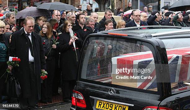 John Amer, father of Acting Sergeant John Paxton Amer of 1st Battalion Coldstream Guards, prepares to step forward to place flowers on the hearse...