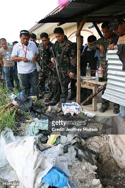 Filipino soldiers look upon seized weapons apparently used in the November 23 massacre which saw 57 people killed at the back of Ampatuan town hall...
