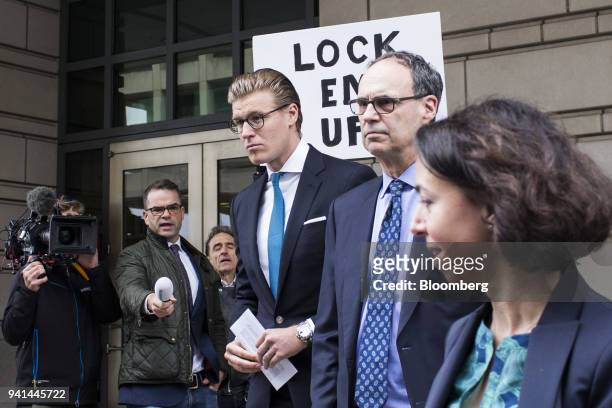 Alex Van der Zwaan, former associate at Skadden Arps Slate Meagher & Flom UK LLP, center, exits as a man holds a sign reading "Lock Em Up!" outside...