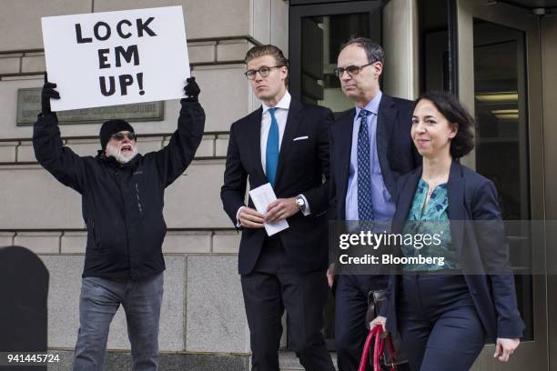 Alex Van der Zwaan, former associate at Skadden Arps Slate Meagher & Flom UK LLP, center, exits as a man holds a sign reading "Lock Em Up!" outside...