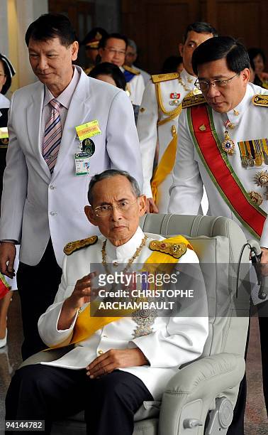 Thai King Bhumibol Adulyadej waves to a crowd of well-wishers as he leaves the Siriraj Hospital on a wheelchair pushed by doctors, in Bangkok on...