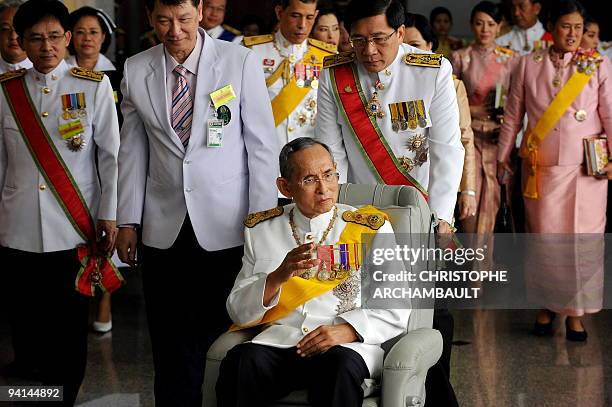 Thai King Bhumibol Adulyadej waves to a crowd of well-wishers as he leaves the Siriraj Hospital on a wheelchair pushed by doctors, in Bangkok on...