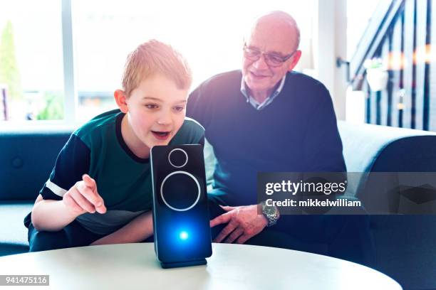 jongen spreekt tot digitale assistent terwijl zijn grootvader die hem kijken - speech recognition stockfoto's en -beelden