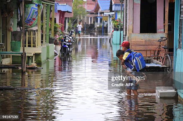 In this photograph taken on December 7, 2009 Indonesian school children walk in a flooded street in Pekanbaru city in the Indonesian province of Riau...
