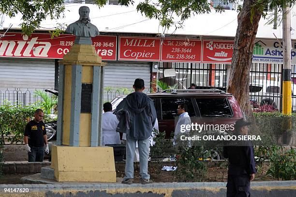 Policemen look for clues in the station wagon where retired general Julian Aristides Gonzalez was assassinated in Tegucigalpa on December 8, 2009....