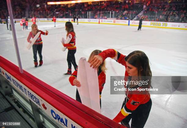 Ice girls apply new advertisements to the boards between periods as the Calgary Flames hosted the Edmonton Oilers on Saturday, March 31, 2018 at the...