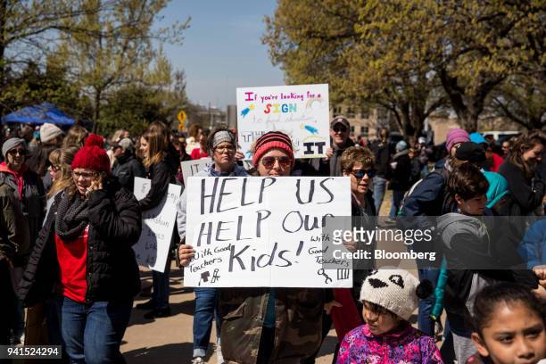 Teachers and demonstrators hold signs during a strike outside the Oklahoma State Capitol building in Oklahoma City, Oklahoma, U.S., on Tuesday, April...