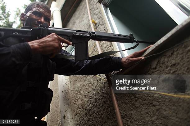 Member of Special Police Operations Battalion tries to gain access to a home while on a patrol searching homes for guns and drugs in the slum, or...