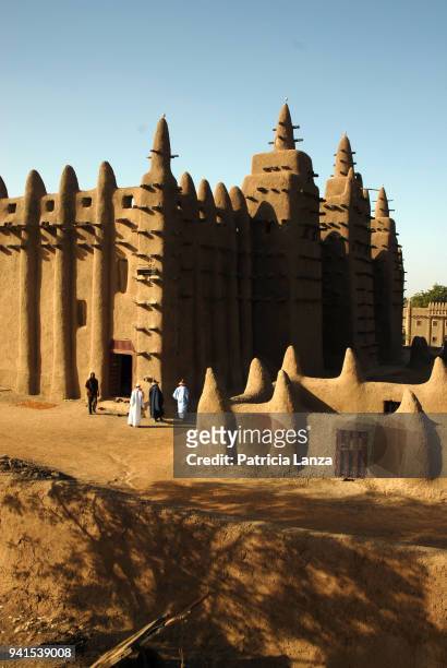 Exterior view of the Great Mosque of Djenne, Djenne, Mali, January 1, 2008. Several men walk near the entrance of the adobe structure.