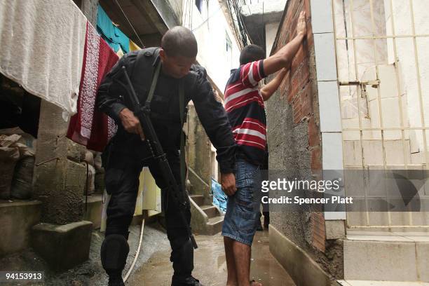 Man is searched by a member of Special Police Operations Battalion while they search homes for guns and drugs in the slum, or favela, Cantagalo in...