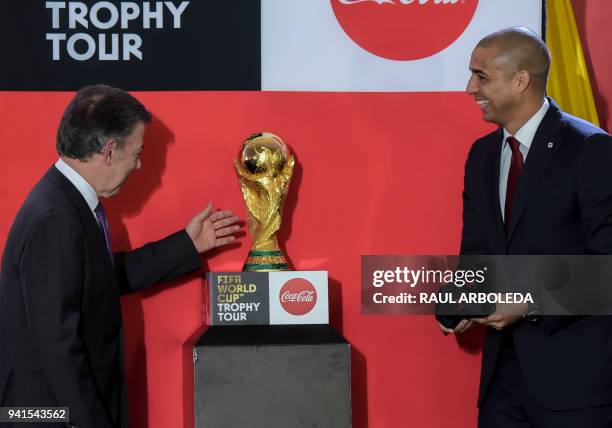 Colombian President Juan Manuel Santos looks the FIFA World Cup trophy next to France's 1998 World Cup Champion, French-Argentine former footballer...