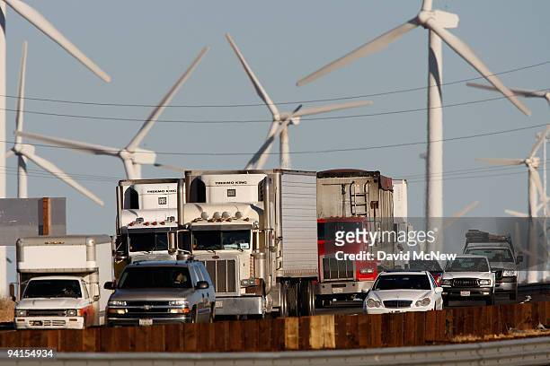 Emissions-producing diesel trucks and cars pass non-polluting windmills along the 10 freeway on December 8, 2009 near Banning, California. Sustained...