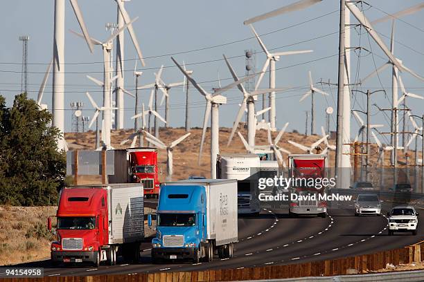 Emissions-producing diesel trucks and cars pass non-polluting windmills along the 10 freeway on December 8, 2009 near Banning, California. Sustained...