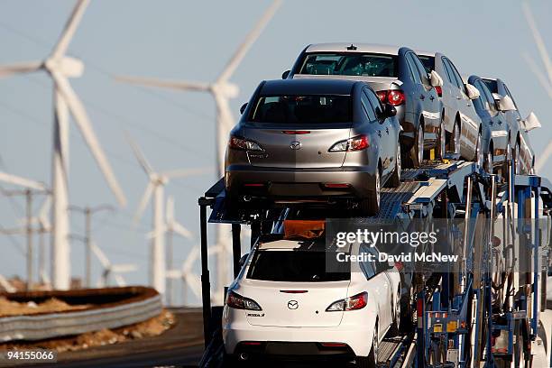 Emissions-producing diesel trucks and cars pass non-polluting windmills along the 10 freeway on December 8, 2009 near Banning, California. Sustained...