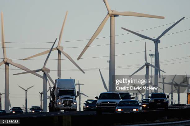 Emissions-producing diesel trucks and cars pass non-polluting windmills along the 10 freeway on December 8, 2009 near Banning, California. Sustained...