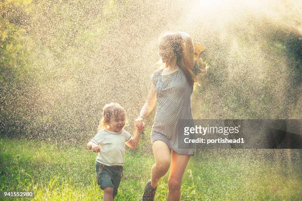 mother and child running in the rain - hot shower stock pictures, royalty-free photos & images