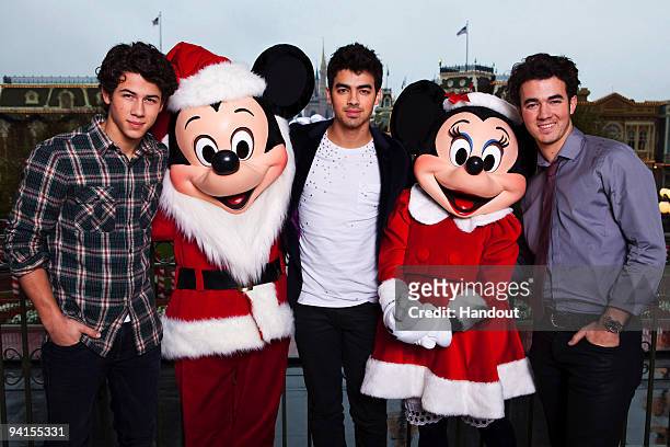 In this handout photo provided by Disney, The Jonas Brothers Nick Jonas, Joe Jonas and Kevin Jonas pose with Mickey and Minnie Mouse on while taking...