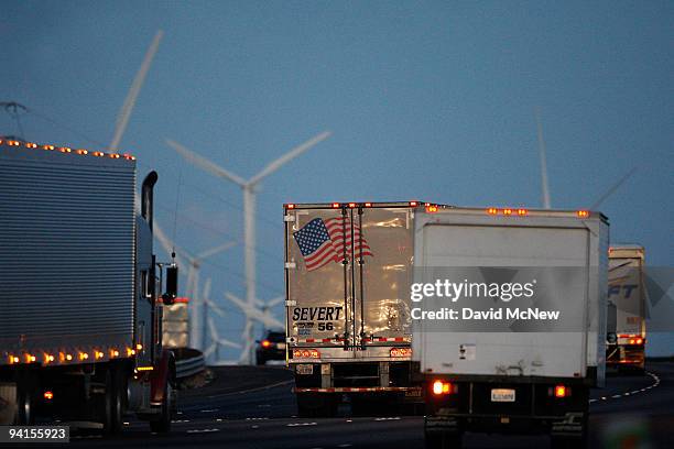 Emissions-producing diesel trucks pass non-polluting windmills along the 10 freeway on December 8, 2009 near Banning, California. Sustained global...