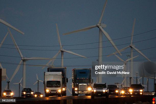 Emissions-producing diesel trucks and cars pass non-polluting windmills along the 10 freeway on December 8, 2009 near Banning, California. Sustained...