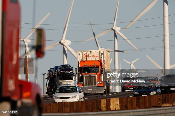 Emissions-producing diesel trucks and cars pass non-polluting windmills along the 10 freeway on December 8, 2009 near Banning, California. Sustained...