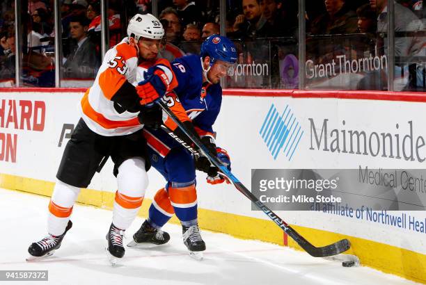 Brock Nelson of the New York Islanders and Shayne Gostisbehere of the Philadelphia Flyers battle for the puck along the boards during the first...