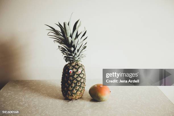 fun food with googly eyes pineapple and mango on kitchen counter - googly eyes stock pictures, royalty-free photos & images