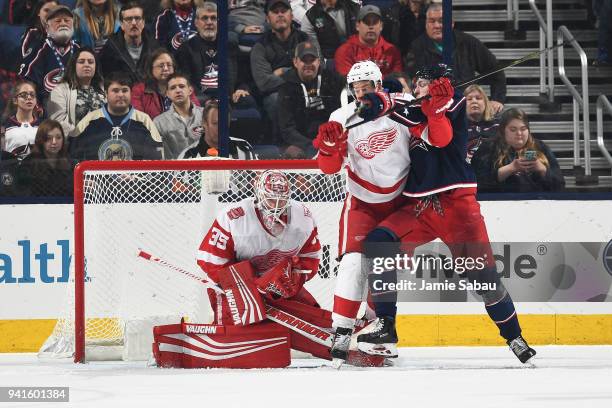 Goaltender Jimmy Howard of the Detroit Red Wings makes a save as Danny DeKeyser of the Detroit Red Wings and Pierre-Luc Dubois of the Columbus Blue...