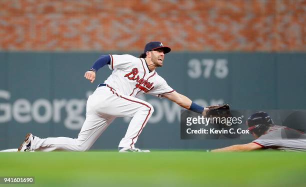 Dansby Swanson of the Atlanta Braves fails to pull in this throw as Trea Turner of the Washington Nationals steals second base in the first inning at...