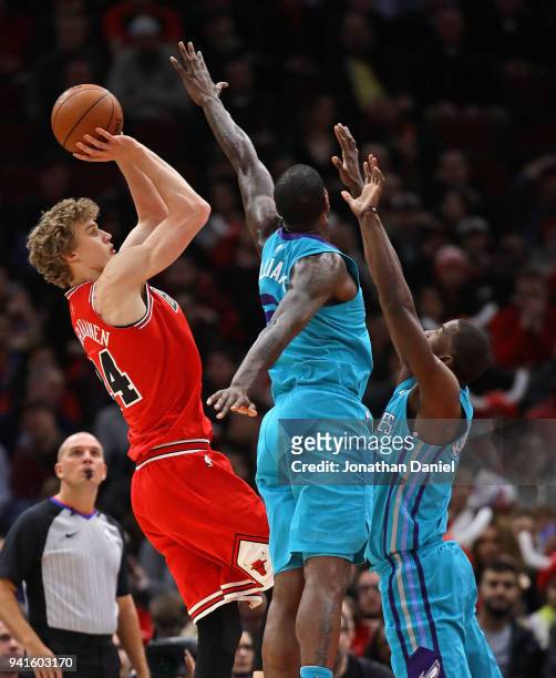 Lauri Markkanen of the Chicago Bulls shoots over Michael Kidd-Gilchrist and Marvin Williams of the Charlotte Hornets at the United Center on April 3,...