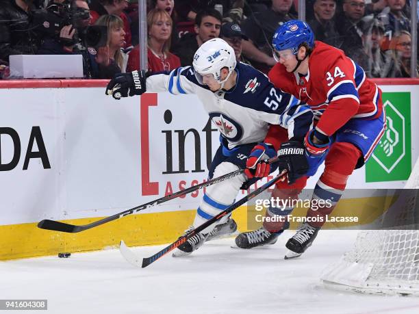 Jack Roslovic of the Winnipeg Jets skates with the puck under pressure from Michael McCarron of the Montreal Canadiens in the NHL game at the Bell...