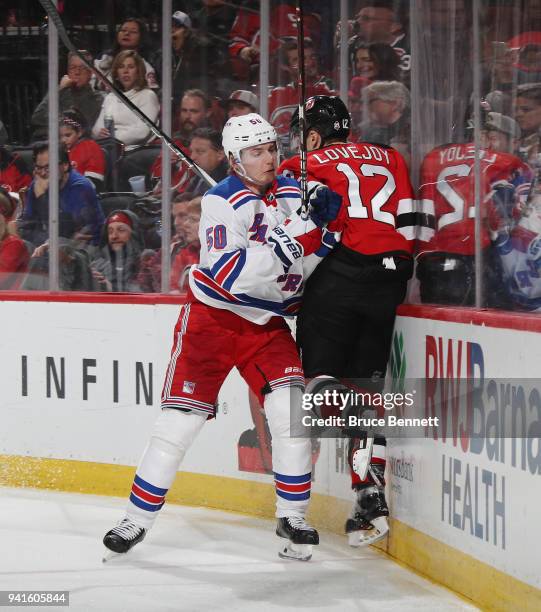 Lias Andersson of the New York Rangers checks Ben Lovejoy of the New Jersey Devils into the boards during the third period at the Prudential Center...