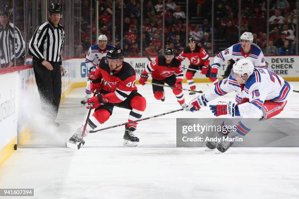 Michael Grabner of the New Jersey Devils battles for the puck against Brady Skjei of the New York Rangers during the game at Prudential Center on...