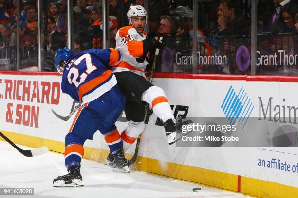 Anders Lee of the New York Islanders checks Brandon Manning of the Philadelphia Flyers into the boards at Barclays Center on April 3, 2018 in New...