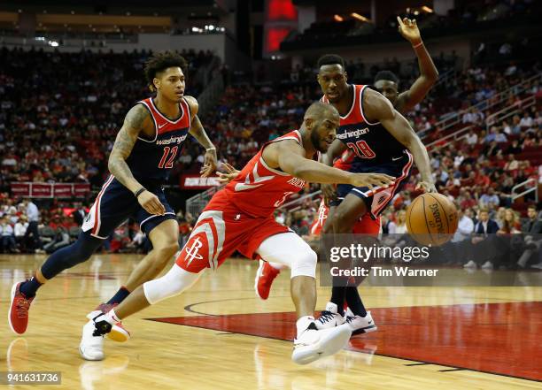 Chris Paul of the Houston Rockets controls a loose ball defended by Ian Mahinmi of the Washington Wizards and Kelly Oubre Jr. #12 in the first half...
