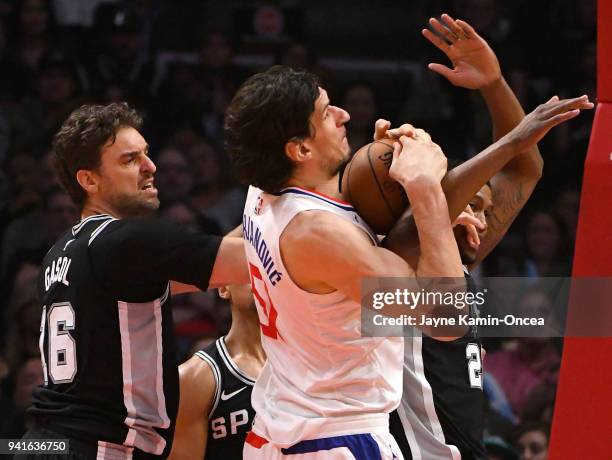 Pau Gasol and Rudy Gay of the San Antonio Spurs defend Boban Marjanovic of the Los Angeles Clippers as he goes for a shot in the first half of the...