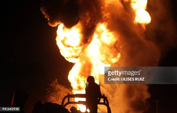 Mexican soldier stands guard while workers of the Mexican state-owned oil company Pemex and local firefighters work to control a fire believed to...