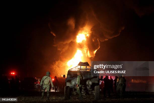 Mexican soldiers stand guard while workers of the Mexican state-owned oil company Pemex and local firefighters work to control a fire believed to...